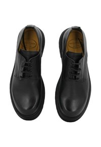 Scarpe in pelle nera con finitura liscia, design con lacci, punte arrotondate e pannelli testurizzati ai lati. Fodera interna gialla.