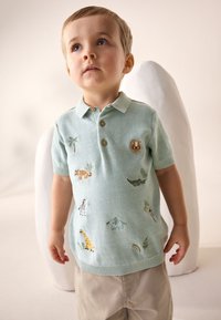 Hele sinine kootud polosärk lühikeste varrukatega, millel on värvikas loomade tikand, kaeluse lukud ja soonikkoes ääred.