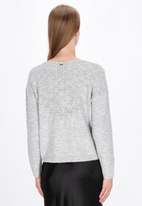 Pulover gri deschis cu un model tricotat texturat pe spate, mâneci lungi, guler rotund și un tiv ușor scurtat.