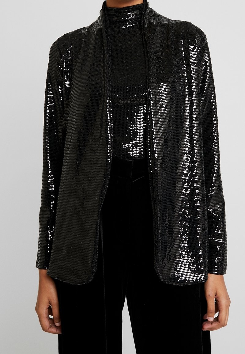 Černá pailletová bunda s uvolněným střihem, dlouhými rukávy a otevřeným předním designem. Hladká textura s třpytivým povrchem po celém obvodu.