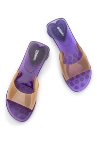 Chanclas moradas con una correa transparente marrón. La plantilla texturizada presenta pequeños patrones de corazones. Están hechas de un material flexible similar al caucho.
