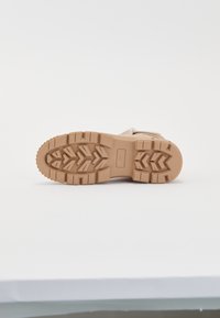 Hnedá gumová podrážka s textúrovaným dezénom, obsahujúcim cik-cak a obdĺžnikové tvary. Ľahká konštrukcia, vhodná na vonkajšie použitie.