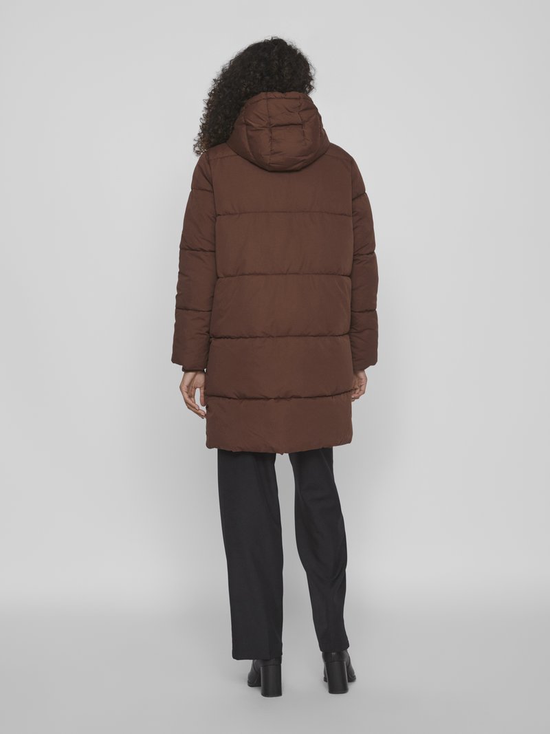 Braune Pufferjacke mit Kapuze, strukturiertem Stoff, horizontalem Steppmuster und mittellanger Passform, kombiniert mit schwarzen Hosen und Absatzstiefeln.