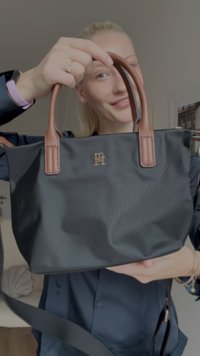 Sort tekstureret tote taske med brune læderhåndtag og logo i guldbelægning. Tasken har et struktureret design og rigelig plads.