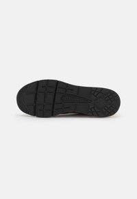 Sneaker-Sohle mit einer strukturierten schwarzen GummOberfläche, ausgestattet mit einem Musterrutschfeste, abgerundete Zehenpartie und leichter Absatzhöhe.