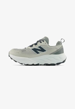 Lichtgrijze en witte sportsneaker met zwarte veters, zwarte zool, gevoerde zool en een donker logo aan de zijkant.