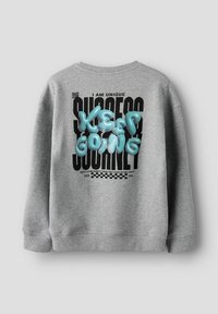 Sudadera gris con letras azules texturizadas que dicen "Sigue Adelante" y texto negro que dice "SOY ÚNICO" y "JOURNEY DE ÉXITO."
