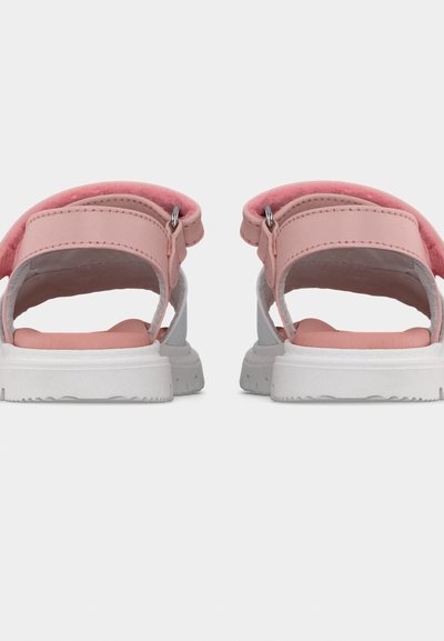 Ζεύγος ροζ και λευκών σανδαλιών με ρυθμιζόμενα λουριά και επενδυμένα πέλματα, εμφανιζόμενα από πίσω σε απλό φόντο.