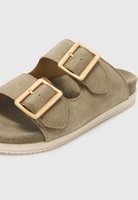 Suede slide sandals in olive green with two gold-tone buckles. Features a cushioned footbed and a textured rubber sole for grip.