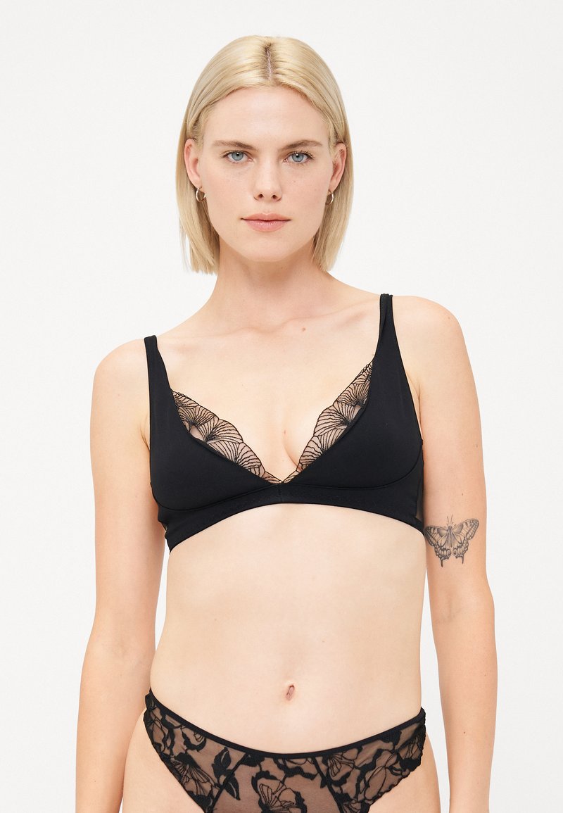 Must musta wireless bralette, millel on sügava V-dekoltee ja pitsist äärisega, koos sobivate šeer mustade aluspesudega, millel on lillemustrid.