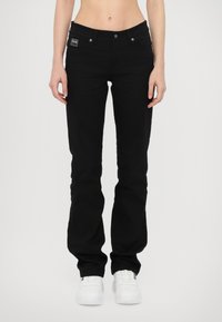 Black denim jeans with a slim fit, five-pocket design, and silver hardware. The fabric has a smooth texture and subtle logo detail on the waistband.