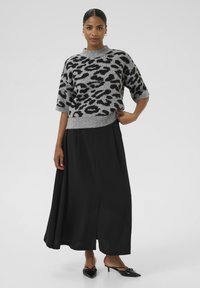 Gray knitted sweater with black leopard print, short sleeves. Paired with a black maxi skirt and pointed black shoes with bows.