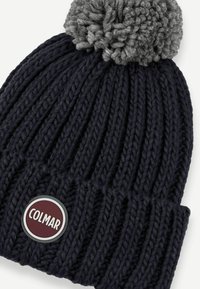 Námořnická modrá pletená čepice s proužky a šedým bambulí na vrchu a kulatou burgundskou nášivkou s nápisem "COLMAR" vpředu na lemu.