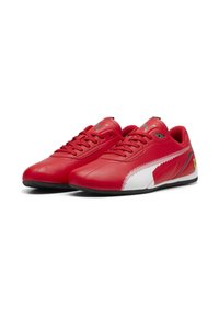 Sneaker Puma rossi con accenti bianchi sui lati, suole nere, logo Puma argentato sulle linguette e logo Ferrari sui talloni esterni.