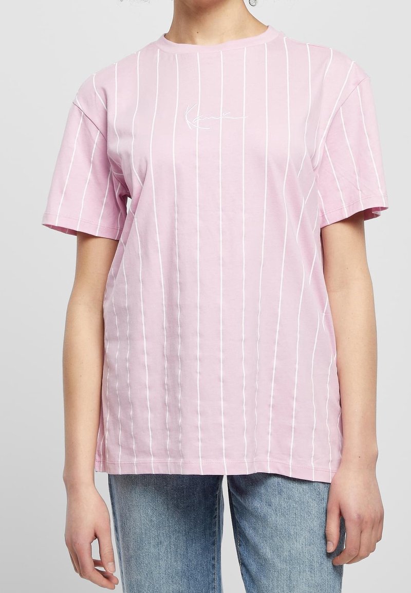 Růžové bavlněné tričko s bílými vertikálními pruhy, krátkými rukávy a kulatým výstřihem. Na přední straně je malé logo.