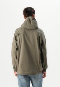 Lett olivgrønn jakke med hette, elastiske mansjetter og sidelommer. Har et minimalistisk design med jevn tekstur og ingen synlig maskinvare.