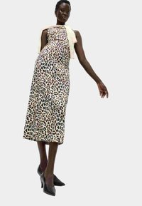 Sukienka w panterkę z dopasowanym gorsetem, długości midi, uszyta z miękkiego materiału. W połączeniu z czarnymi szpilkami i jasnym szalem.