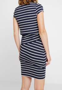 Granatowo-biała sukienka w paski, z dopasowanym krojem i krótkimi rękawkami. Gładka tkanina o lekko elastycznej strukturze.