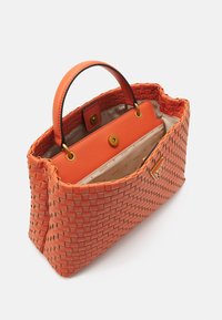 Tkaná korálová kabelka s texturovaným designem, dvojitými uchy a kontrastním oranžovým koženým interiérem, který obsahuje zapínací kapsu.