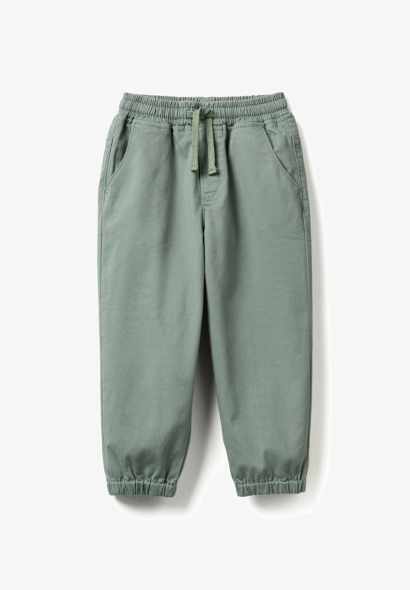 Grüne Jogginghose mit elastischem Bund, Kordelzug und elastischen Bündchen, mit zwei Vordertaschen, flach auf weißem Hintergrund ausgebreitet.