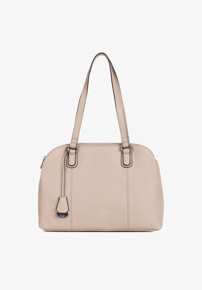 Beige leren tote bag met dubbele handvatten, subtiele stikdetails en een afneembare tag. Glad van textuur en gestructureerde vorm.
