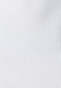 Fehér bordás textil mintázat, amely függőleges vonalakat mutat be. Az anyag simának tűnik, enyhe fényességgel, ami rugalmasságot és puhaságot sugall.