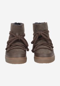 Bottines en suede marron avec de grosses lacets tressés. Doublure douce, bout arrondi et semelle en caoutchouc avec des détails texturés. Pas de marque visible.