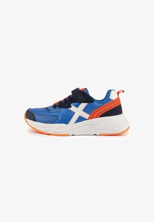 Blauwe sportschoen met een witte kruis, oranje accenten, een klittenbandriem en een gestructureerde bovenkant met een solide rubberen zool.