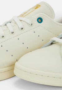 Lichtcrème leren sneakers met perforatie details, platte veters en een contrasterend turkoois oogje. Rond neu en gestructureerde zool.