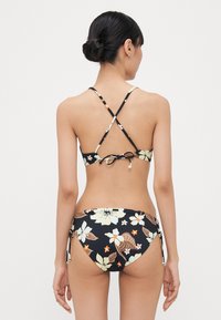 Black floral bikini featuring a crisscross back design, adjustable ties, and a mix of large and small floral patterns in cream, brown, and orange.