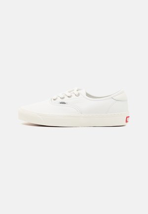 Witte leren lage sneakers met een ronde neus, vetersluiting aan de voorkant, subtiele stiksels en een rood logolabel op de hiel. Glad oppervlak, eenvoudig ontwerp.