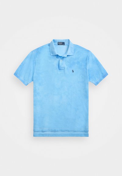 Vaaleansininen polo-paita pehmeästä kankaasta, jossa on kaulus, lyhyet hihat ja pieni logo vasemmassa rinnassa.