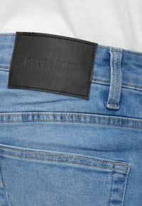 Ανοιχτό μπλε τζιν με υφή σε μαύρη δερμάτινη ετικέτα ραμμένη στο πίσω μέρος, με την επωνυμία "ONLY & SONS", και κανονικές πίσω τσέπες.