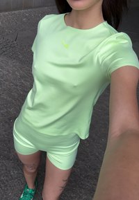 Ljusgrön träningsset gjort av ett slätt, stretchigt material; inkluderar en kortärmad topp med en liten Nike-logga och matchande shorts.