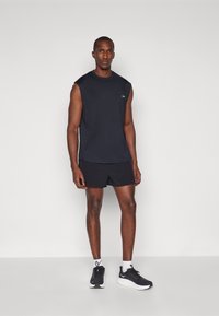 Black sleeveless athletic top, black shorts, and black sneakers with white accents. The fabric appears lightweight and suitable for sports.