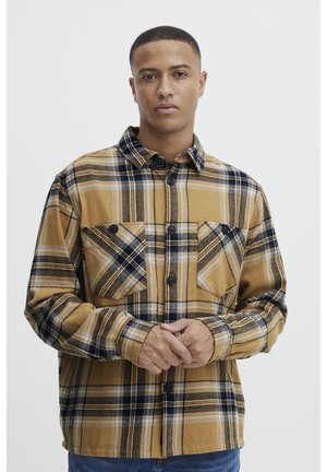 Chemise à carreaux brune avec des accents bleus et crème, dotée de deux poches avant, d'une fermeture à boutons et d'un design de col classique.