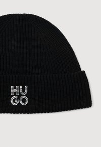 Beanie a coste nera con risvolto, adornato con strass argentati che formano le lettere "HUGO" sul lato sinistro davanti.