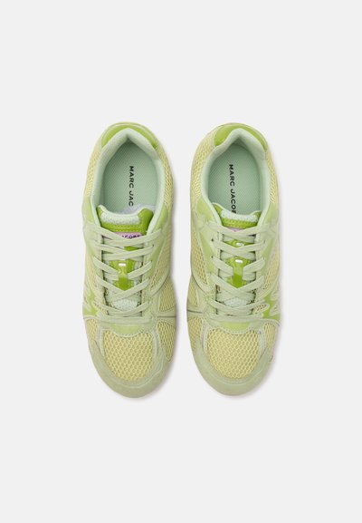 Paire de baskets en mesh vert clair avec lacets, marque Marc Jacobs visible sur les semelles intérieures, vues de dessus sur fond blanc.