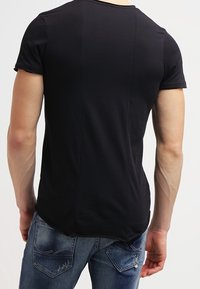 Sort kortærmet t-shirt med en tætsiddende design, der har en rund halsudskæring og en glat tekstur, parret med blå denim jeans.