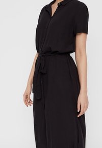 Black short-sleeve dress, button-up front, belted waist, soft fabric with a smooth texture, knee-length, straightforward design.