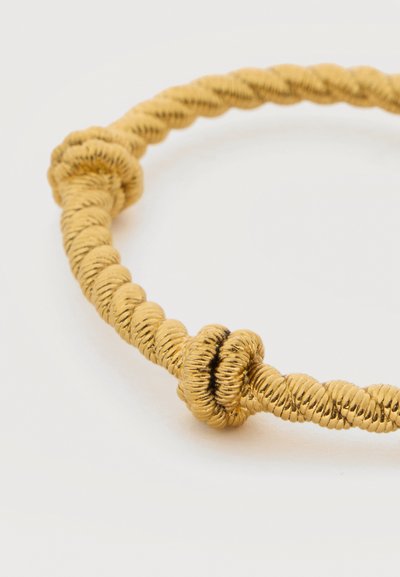 Βραχιόλι από χρυσό στριφτό σχοινί με δύο λεπτομέρειες κόμπου σε λευκό απλό φόντο, που αναδεικνύει την υφή και το σχέδιο.