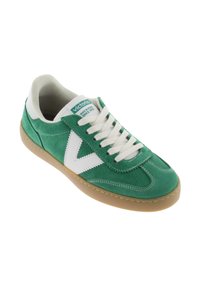 Gröna mockaskor med en vit tygtunga, vita detaljer och gummisulor. Har snörning och en logga på tungan.