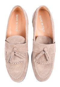 Mocassini in suede beige con punta arrotondata, caratterizzati da un accento a nappe e dettagli cuciti. L'interno è in pelle, etichettato "Made in Italy."