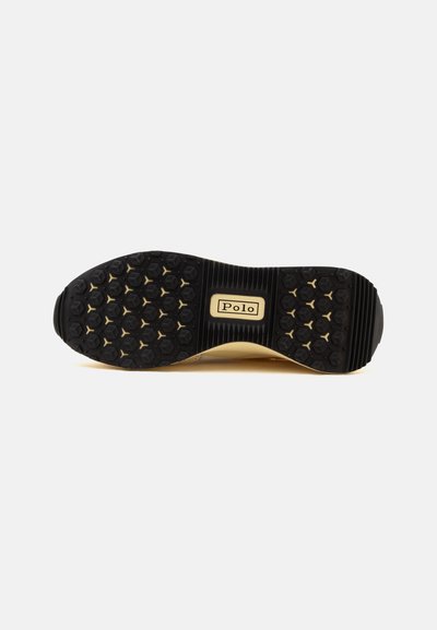 Semelle de chaussure noire avec motif hexagonal de la bande de roulement et étiquette "Polo" au centre sur fond beige.