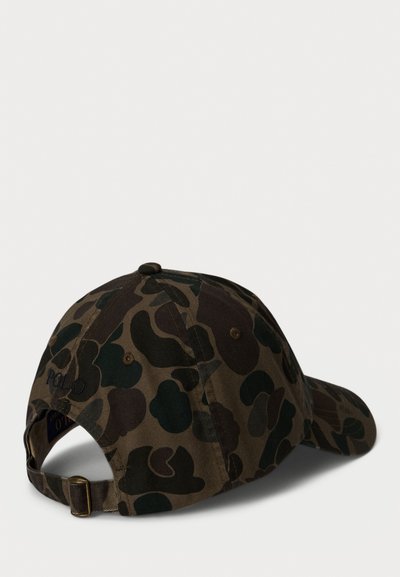 Camo vzorovaná baseballová čiapka v tmavozelenej a hnedej farbe. Obsahuje nastaviteľný pásik, zaoblenú korunu a vyšitý logo "POLO".