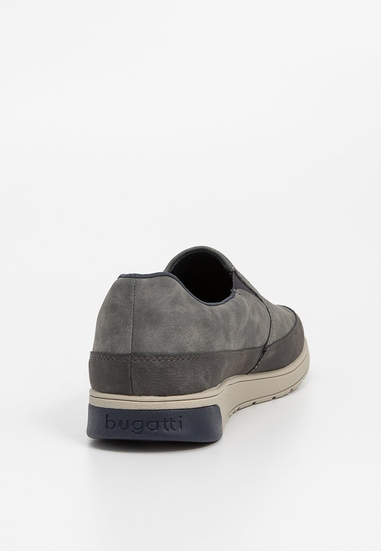 Chaussure slip-on en daim gris avec une forme arrondie, semelle beige et accents bleu marine. Présente des coutures minimales et un logo de marque sur le talon.