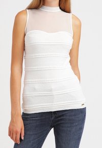 Top bianco senza maniche con collo alto trasparente e righe orizzontali testurizzate. Presenta una silhouette aderente e un sottile accento del marchio.