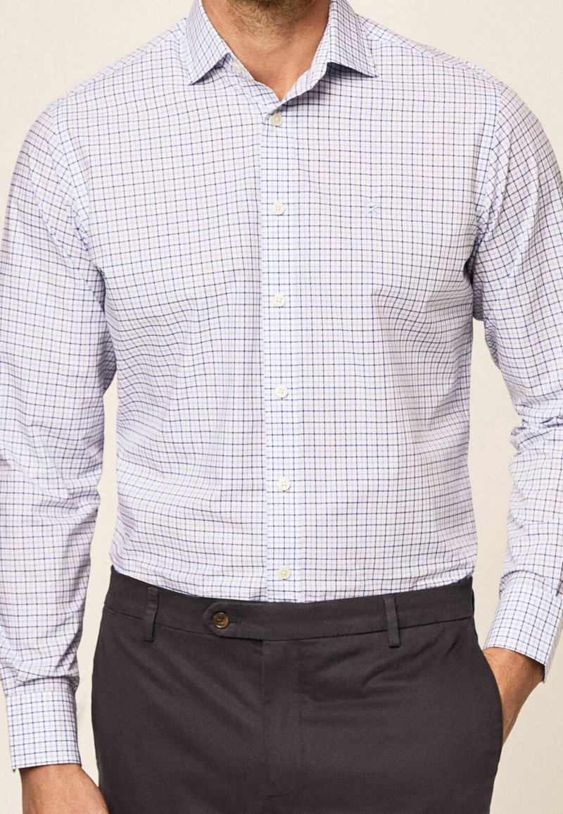 Geruit dressshirt met een blauw en witte rasterpatroon, met knoopsluiting, lange mouwen en lichte stof, gecombineerd met donkere broek.