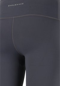 Korkeavyötäröiset tummanharmaat legginsit, joissa on sileä ja joustava kangas, tasasaumakohdat ja hillitty logo vyötäröllä.