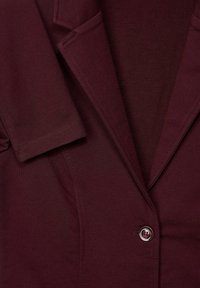 Burgundy kavaj med slagkrage, korta ärmar och stängning med en knapp. Mjuk tyg med en slät yta.